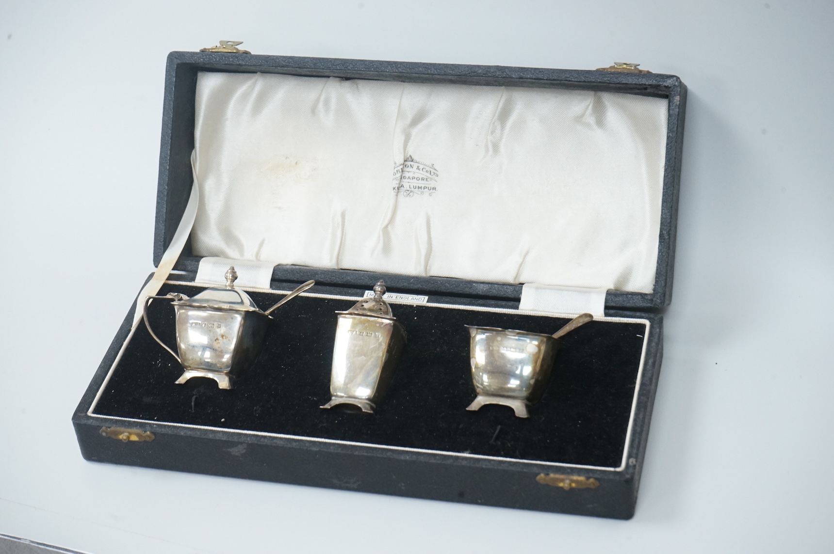 A pair of cased Elizabeth II silver three piece condiment sets, by William Adams Ltd, Birmingham, 1955, one spoon missing.